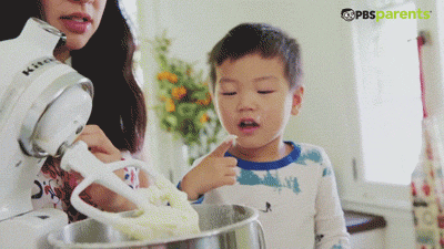 kid tasting batter from mixer in the kitchen
