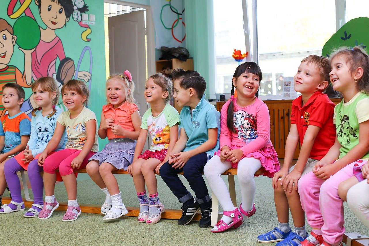 Kindergarten kids sitting on a bench in a classroom